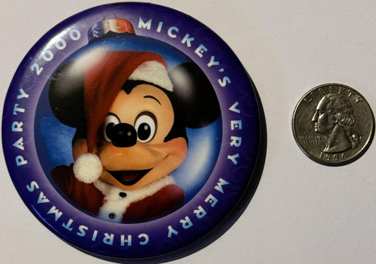 Circular purple pin featuring Mickey Mouse in Santa hat, with quarter coin for scale, text reading "2000" and "Mickey's Very
