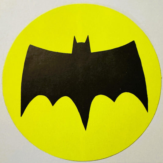 Black bat silhouette with pointed ears on bright yellow circular background, vintage sticker or decal