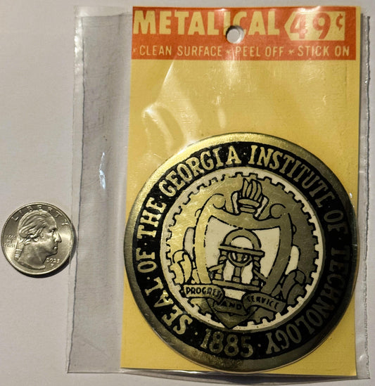 Vintage metallic Georgia Institute of Technology decal on yellow backing with quarter for scale, next to clear protective sle