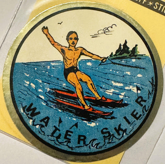 Circular water skier decal showing a shirtless man in orange and black skis on blue water with trees and clouds, mounted in g