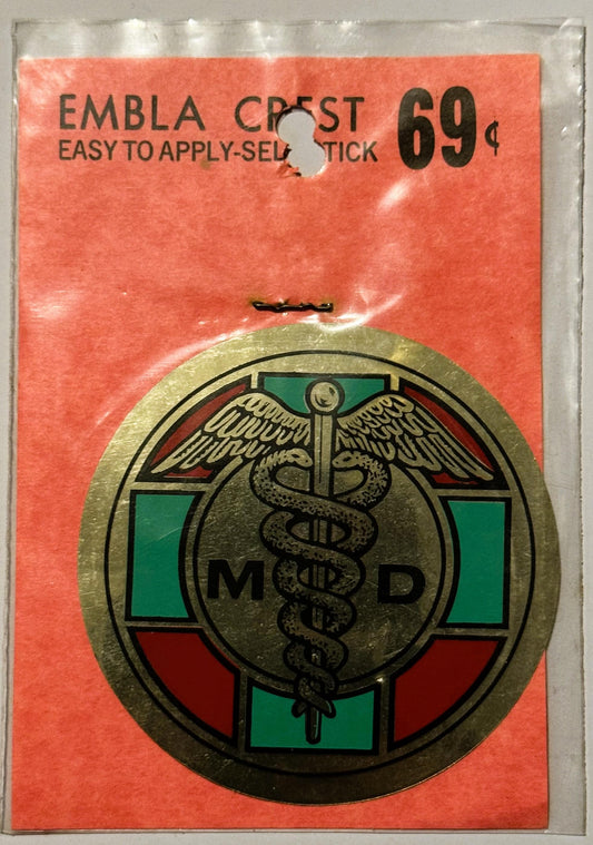 Vintage medical emblem decal on orange backing card showing caduceus symbol with "MD" text and green/red colored sections, pr