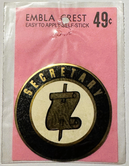 Unopened vintage self-stick emblem crest decal on pink card stock priced at 49 cents, featuring circular black and cream seal