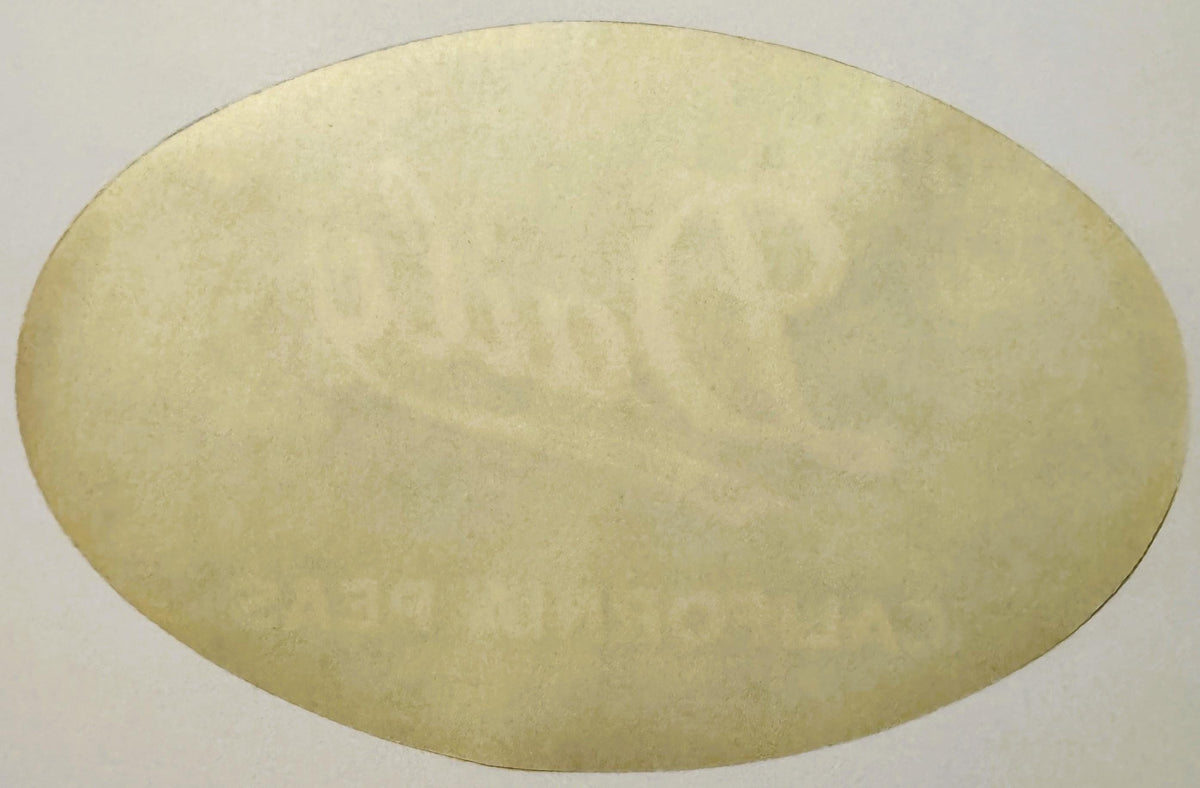 Blank cream-colored oval vintage crate label with embossed texture, photographed flat against white background
