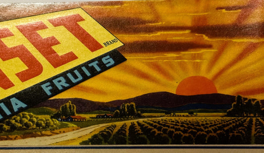 Close-up of vintage fruit crate label with yellow and red geometric design, "Sunset Brand" text on black band, agricultural l