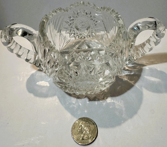 Antique cut glass two-handled sugar bowl with geometric patterns, displayed with a quarter dollar for scale