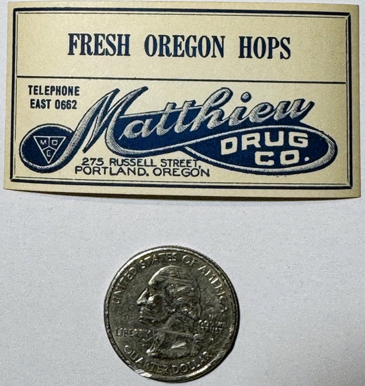 Vintage cream and navy drug store label for Matthew Drug Co., Portland Oregon, next to a US quarter for scale