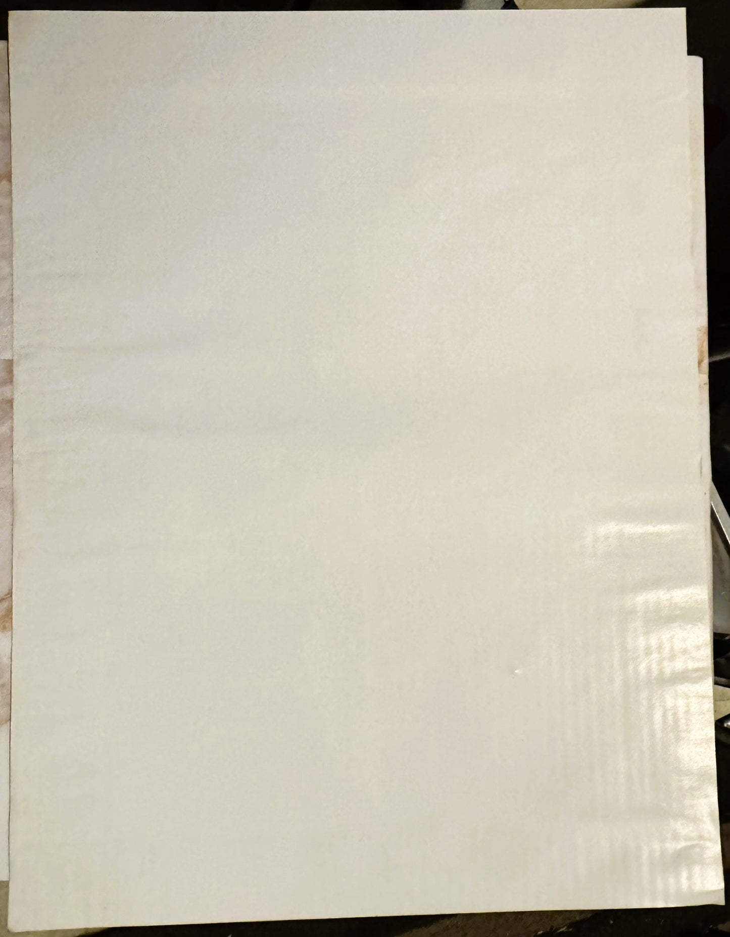Blank cream-colored poster page photographed flat against dark background, showing wear marks and creases along right edge