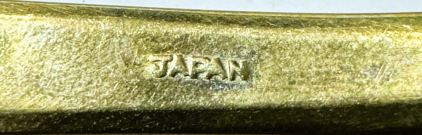 Close-up of embossed "JAPAN" marking on textured gold-tone brass flatware handle