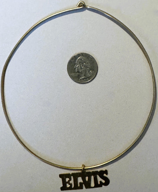 Gold-tone choker necklace with quarter coin for scale, black "ELVIS" nameplate charm pendant at bottom