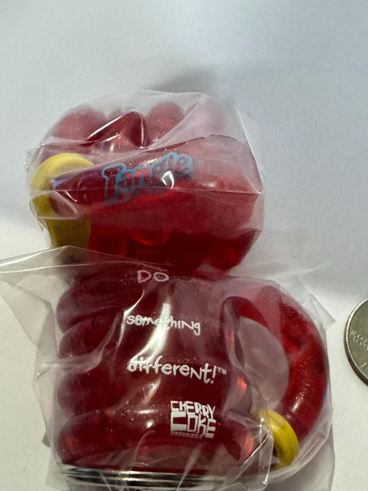 Two sealed red Cherry Coke Tangle fidget keyrings in plastic packaging with yellow accents, photographed next to a coin for s