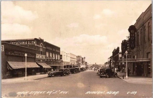 Sepia-toned street view of Auburn, Nebraska showing Main Street with Thygeson & Glen drugstore and period automobiles from ap