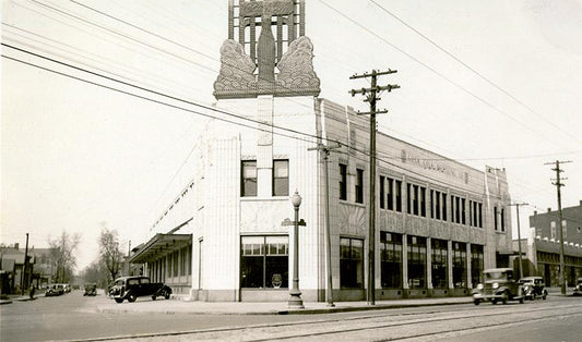 Black and white photo of a distinctive Art Deco building with tower in Indiana Harbor, circa 1930s-40s, with vintage cars par