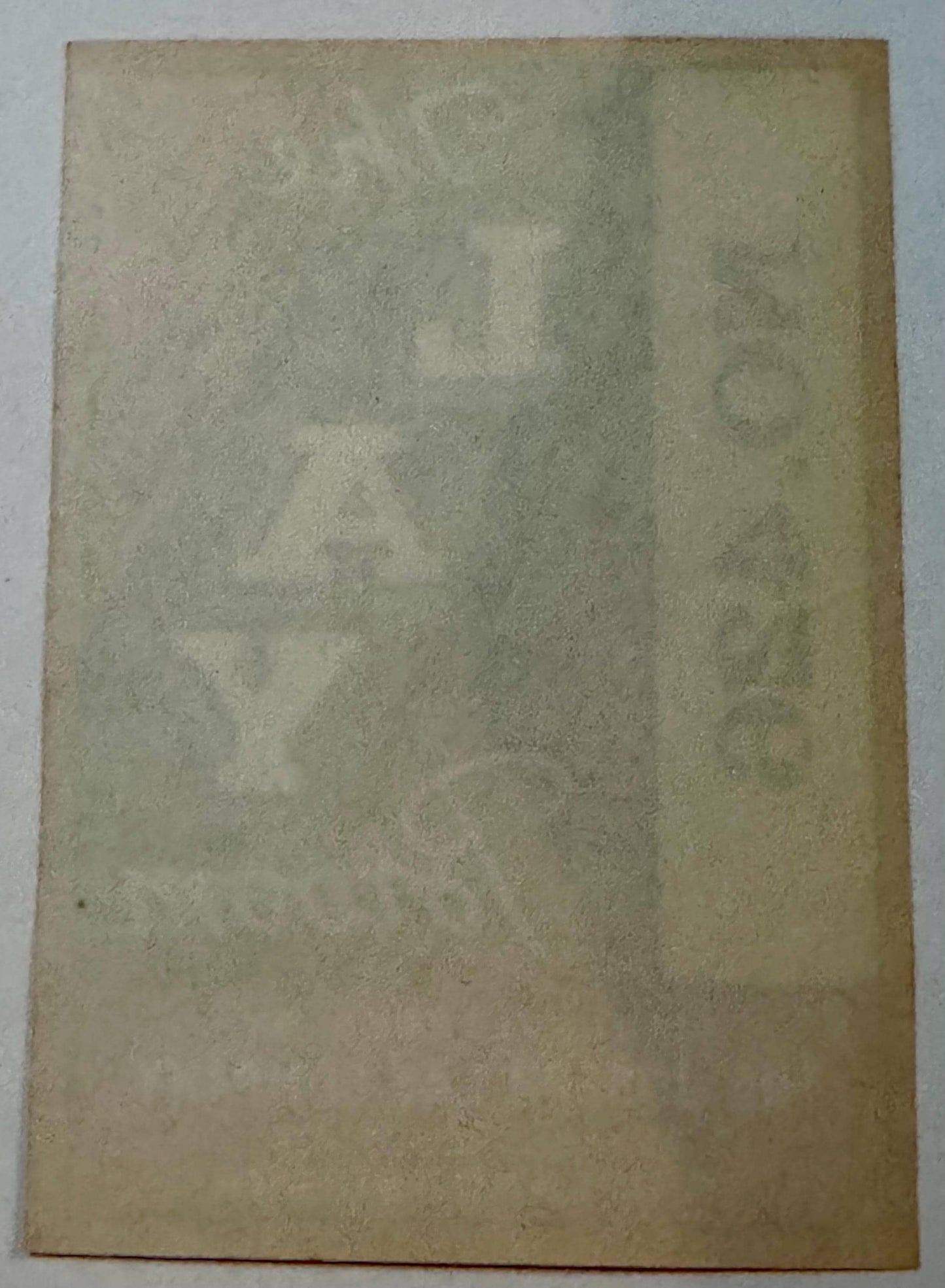 Faded aged paper label showing ghost impressions of text through the reverse side.