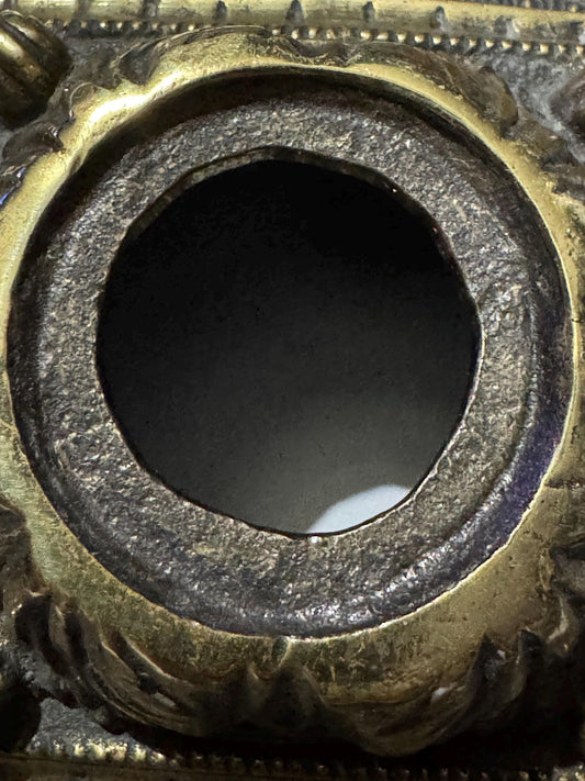 Macro close-up straight down into the second bare, unlined brass well
