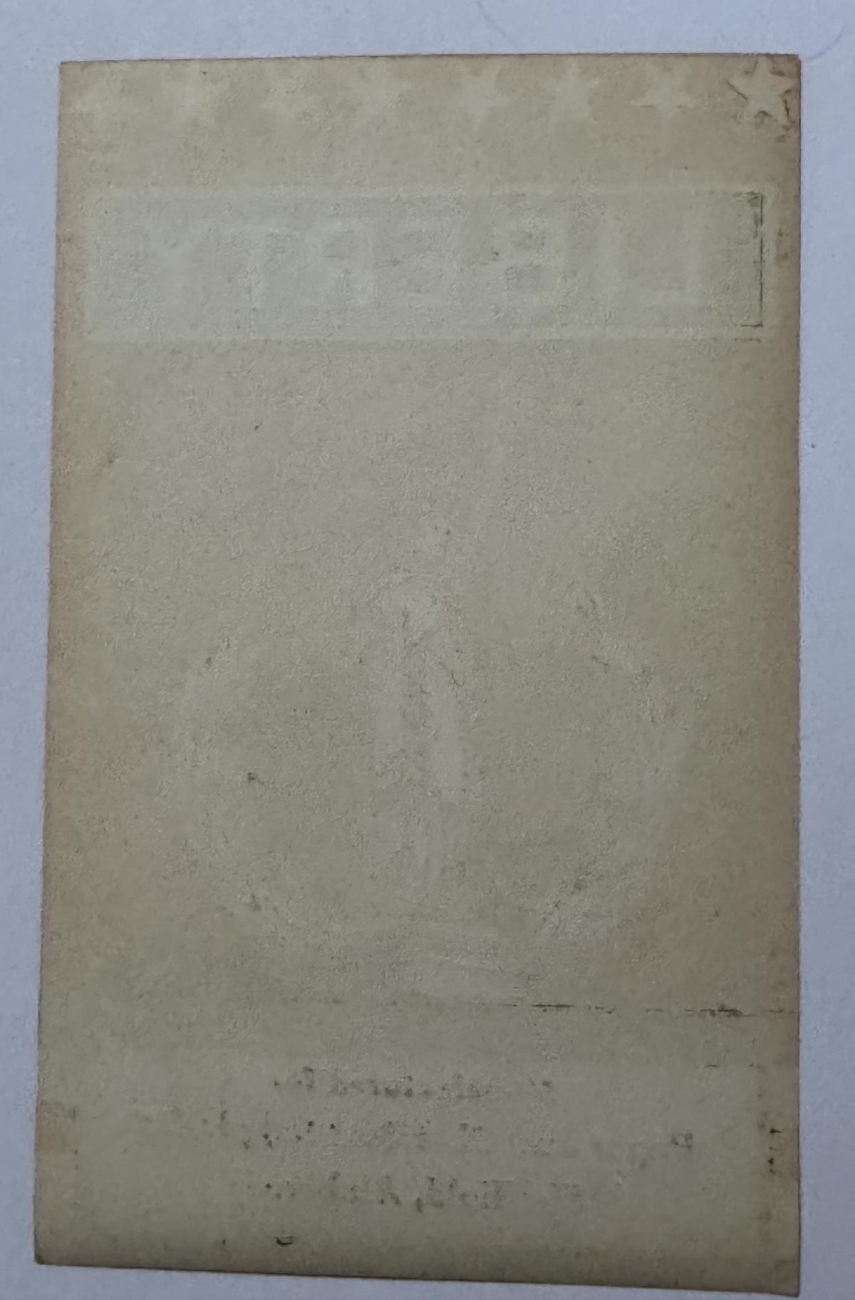 Blank back of the LIBERTY broom label with the star, lettering and imprint lines showing through the paper