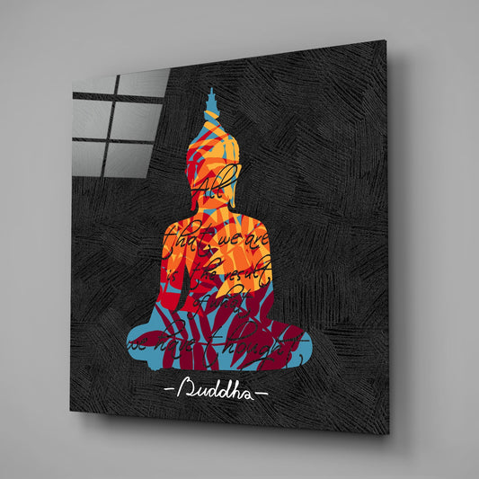 Angled view of glass wall art displaying a colorful silhouette Buddha figure in orange, red, and blue tones with handwritten text overlay on dark textured background.