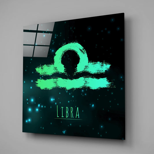 Angled view of teal glass wall art displaying neon green Libra symbol with brushstroke texture on dark starry background.