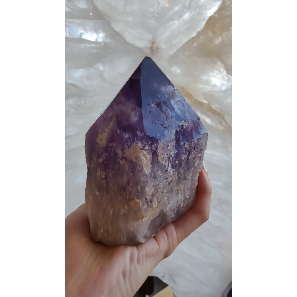 Hand holding large Bolivian amethyst point from Anahi Mine with deep purple hues