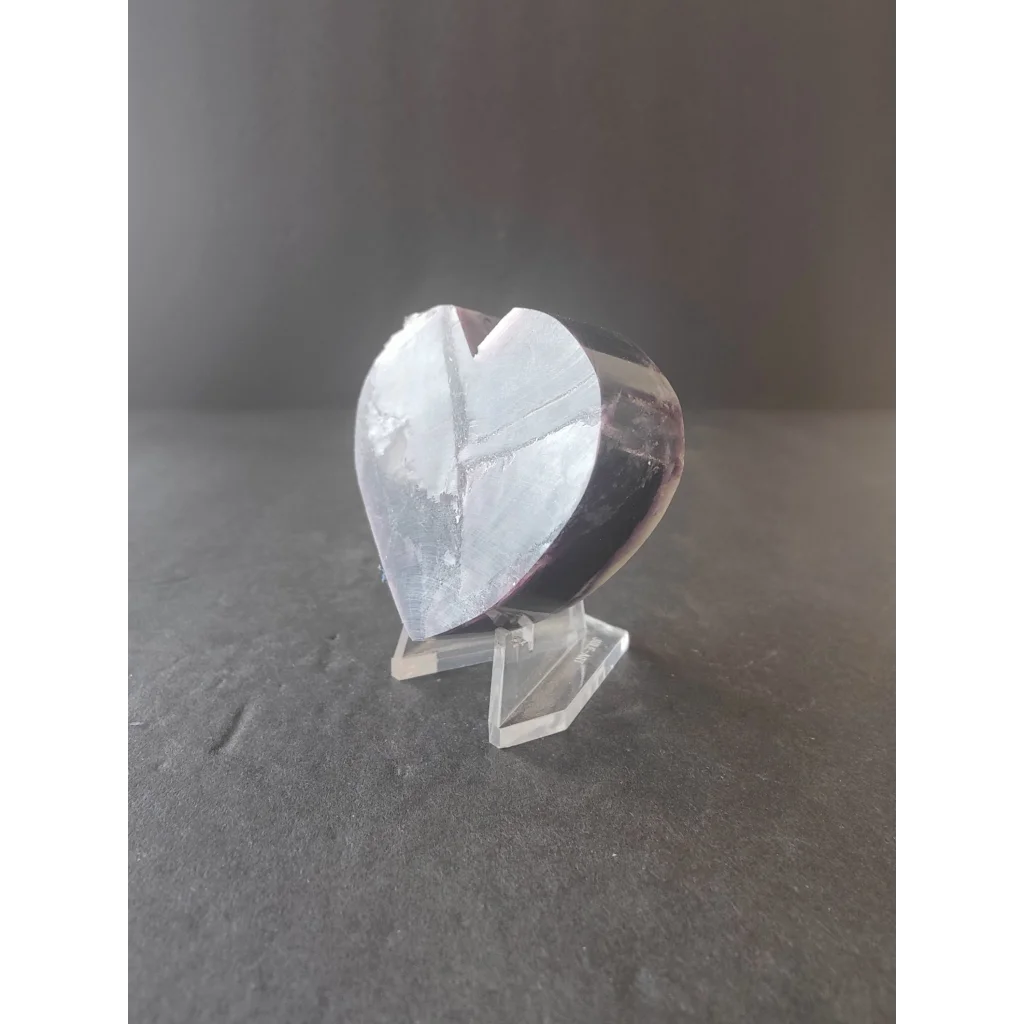 A translucent heart-shaped lepidolite crystal sculpture with a smooth polished surface and subtle internal reflections