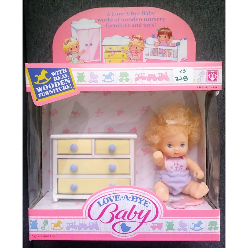 Vintage 1987 Love-a-Bye Baby Doll with blonde curls in purple dress on wooden dresser