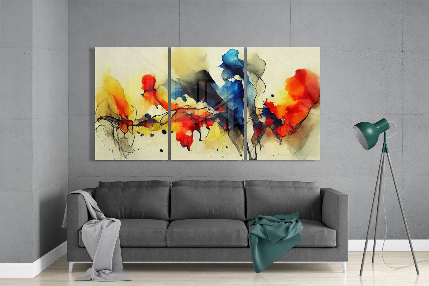 Three-panel abstract watercolor glass art with red, yellow, and blue ink dispersal displayed above gray sofa in modern living room.