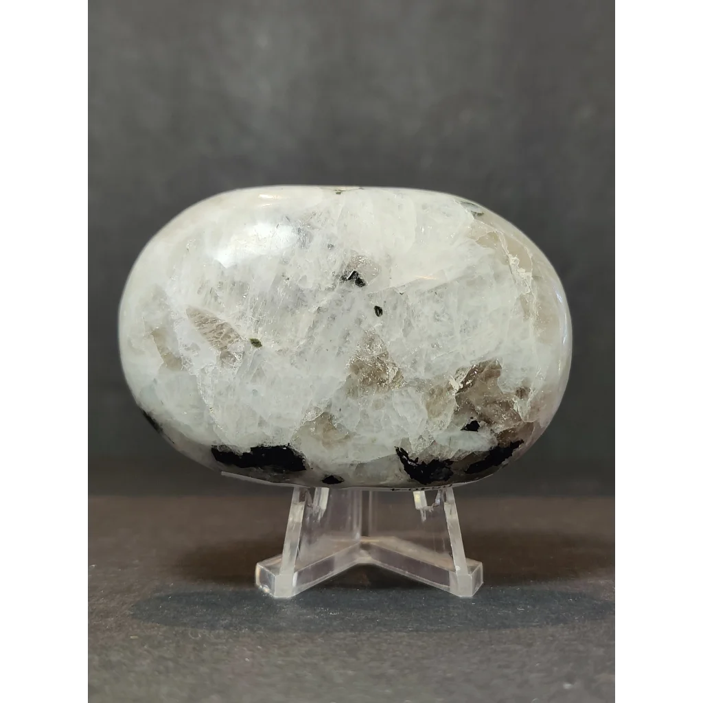 Moonstone polished heart and palmstone sculpture with smooth white quartz and black metallic inclusions on acrylic stand