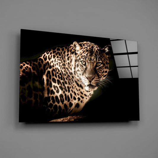Angled perspective of glass wall art displaying a sepia-toned leopard portrait against black background with visible grid pattern on glass edge.