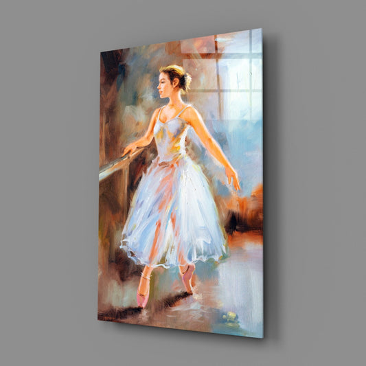 Glass wall art panel displaying a ballet dancer in a white tutu at a barre, painted in impressionistic style with warm and cool tones, angled view showing three-dimensional depth.