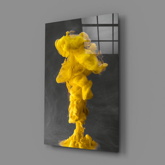 Glass wall art mounted at an angle displaying a vibrant yellow ink plume suspended against a dark gray background with grid overlay.