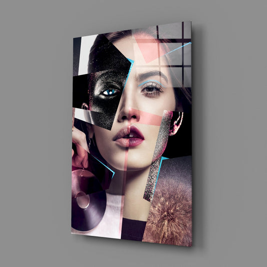 Angled view of glass wall art featuring a woman's face in collage style with glitter accents, cyan lines, pink overlays, and black geometric shapes against gray background.