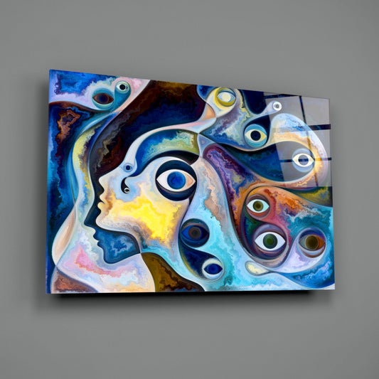 Colorful glass wall art featuring abstract blue and yellow profile faces with metallic circular eye details, mounted on gray wall.
