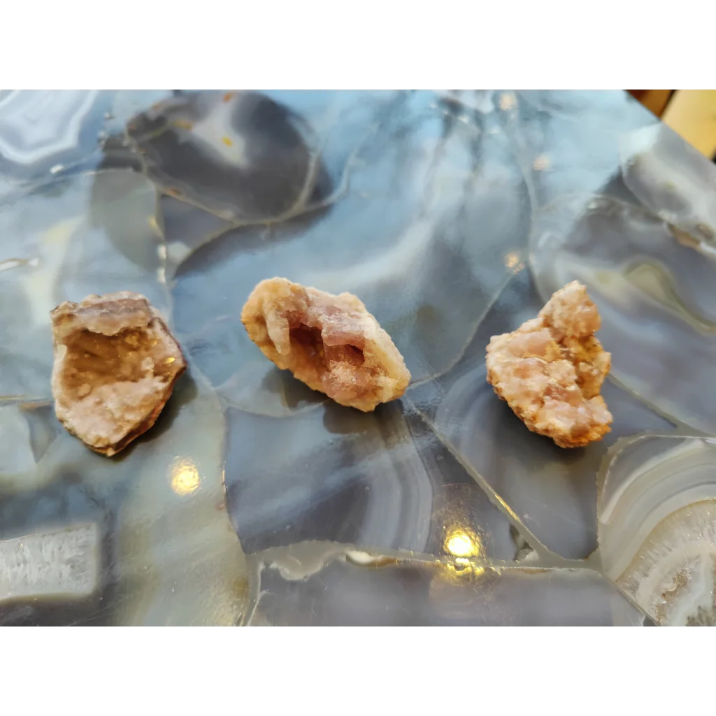 Three light brown geodes on pink amethyst agate slab