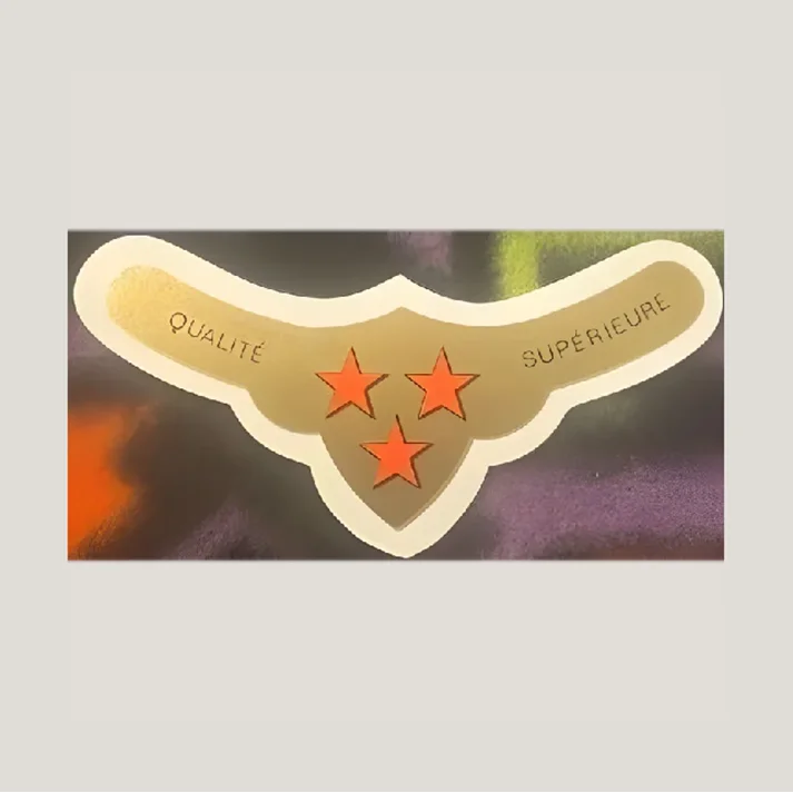 Gold shield-shaped French wine label with three orange stars and text reading Qualité Supérieure on colorful background