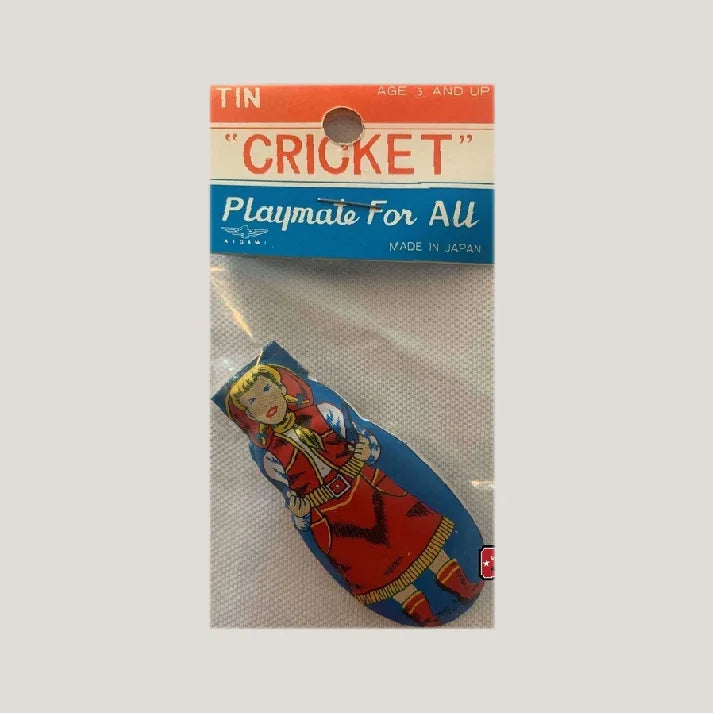 Packaged vintage tin cricket clicker toy featuring girl in red, labeled "CRICKET Playmate For All."