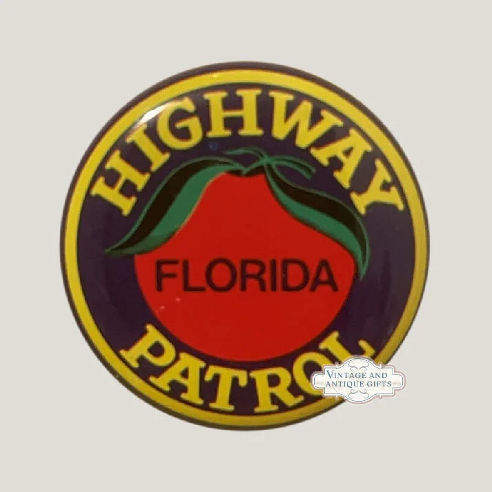 Close-up of the round Florida Highway Patrol toy badge: yellow border, navy field, red-orange citrus orange with green leaves and FLORIDA lettering.