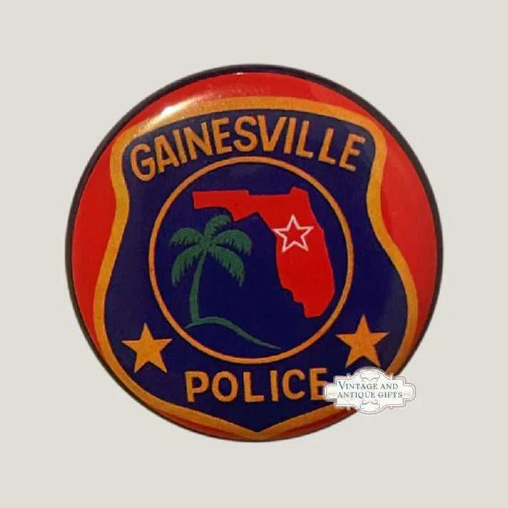 Circular red and navy Gainesville Police badge pin featuring Florida map, palm tree, stars.