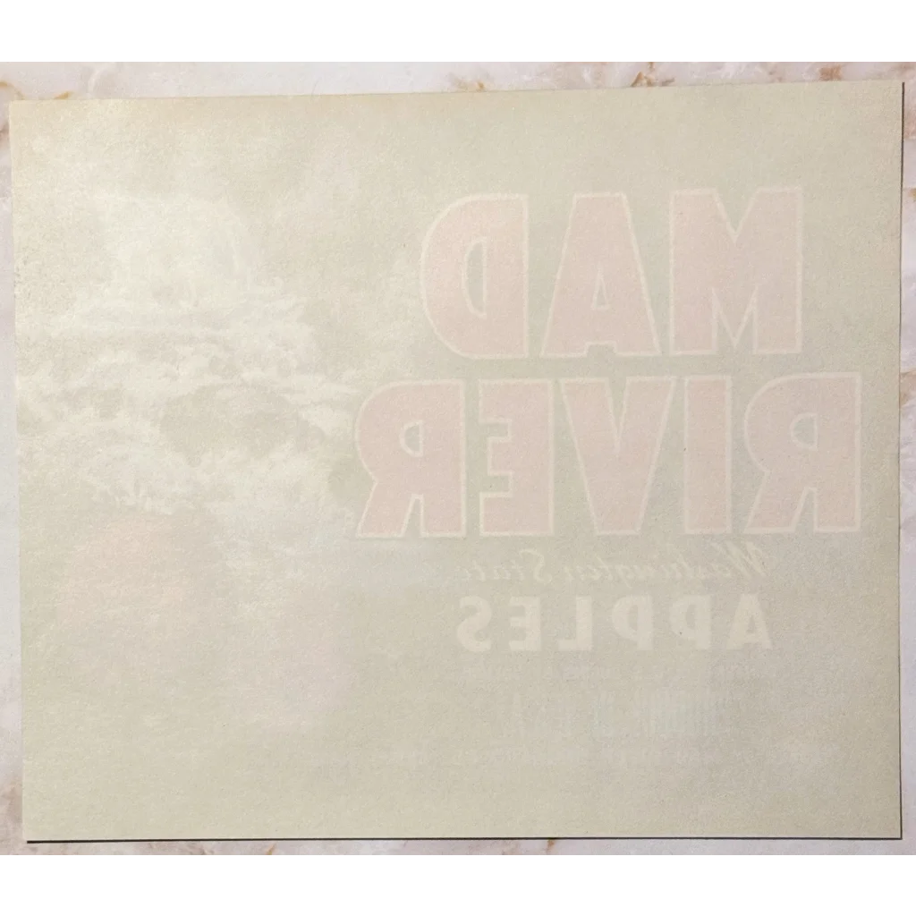 Faded white text backwards on a light surface of Rare 1950s Mad River Apple Label