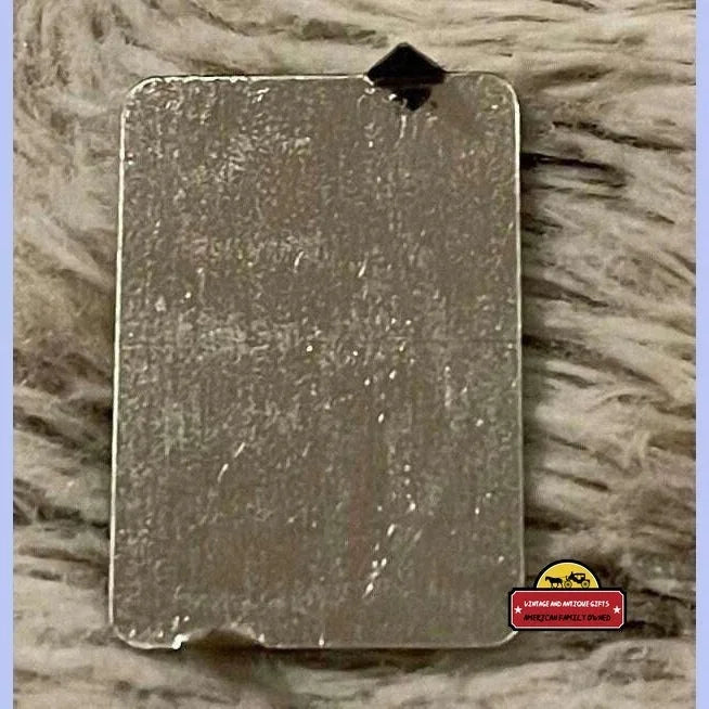 Worn black Maria tin tobacco tag from the 1870s with a scratched surface and small hole