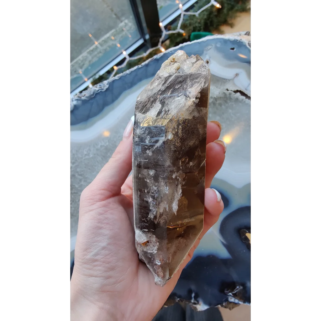 Hand holding rare Brazilian smokey quartz point with lodalite inclusions