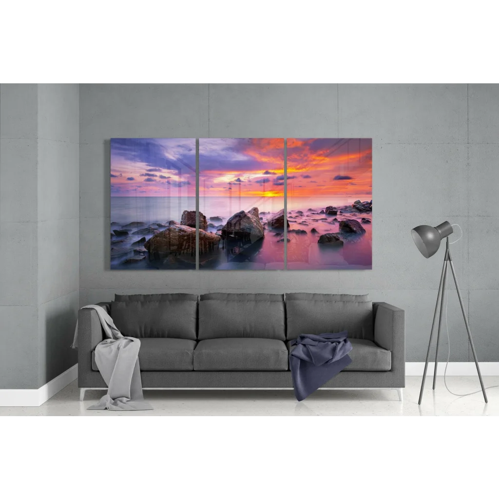 Vibrant sunset seascape glass wall art triptych above gray sofa