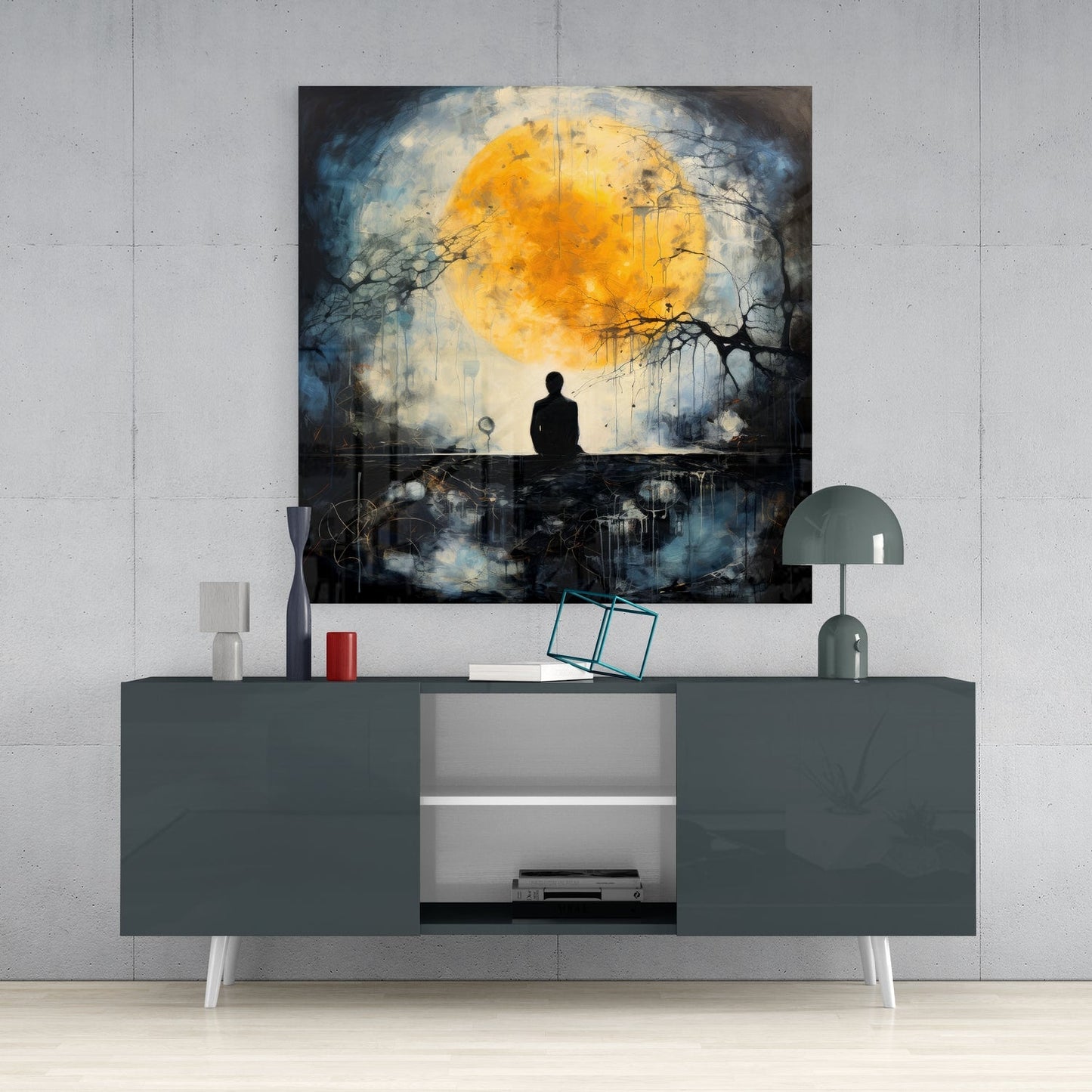 Glass wall art depicting a silhouetted figure beneath a golden moon with dark branches, displayed above a gray media console.