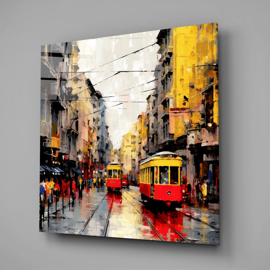 Modern glass art panel mounted on gray wall showing impressionist street scene with red and yellow trams on wet urban avenue.