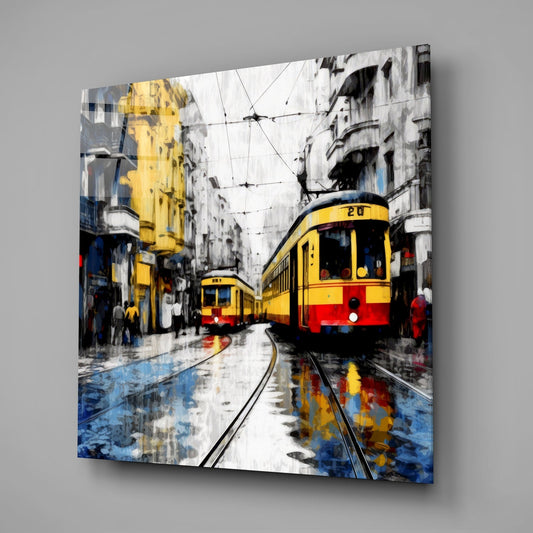 Yellow and red tram on wet street tracks with grey buildings and blue water reflections, displayed as glass wall art mounted on grey wall.