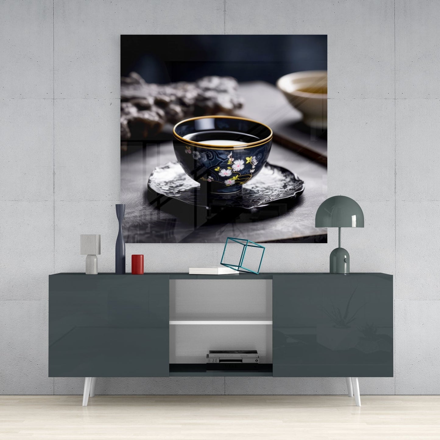 Dark porcelain tea bowl with gold rim and floral design displayed on textured black coaster in styled room setting.