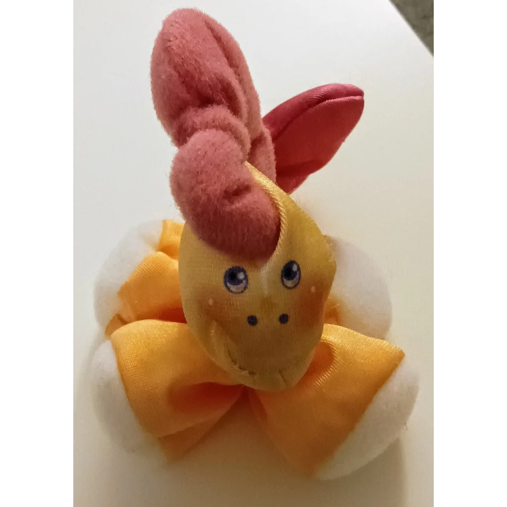 Cute yellow and orange Smooshees Critters Prancy Pony plush toy with pink ears on white surface