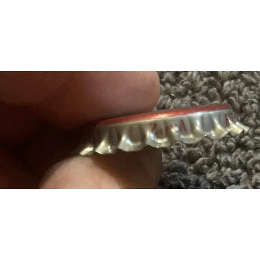 Crimped metal bottle cap of Rare 1970s Caravan Strawberry Soda held between fingers