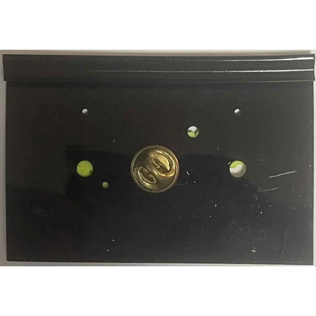 Black block logo pin with gold emblem and green dots, perfect for collectors