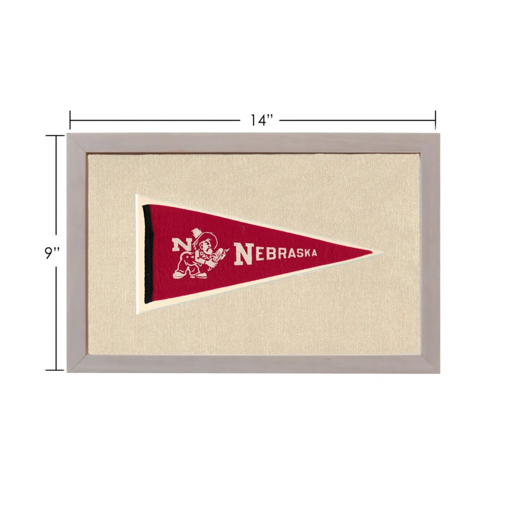 Vintage Nebraska pennant with red design, white lettering, and cartoon mascot in gray frame