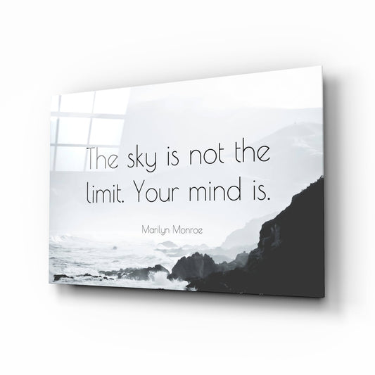 Glass wall art panel displaying Marilyn Monroe quote overlaid on coastal ocean and rocky cliff photograph in black and white.