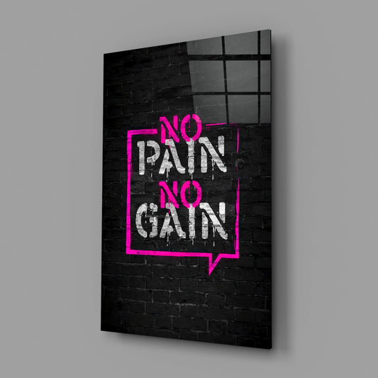 Angled three-quarter view of glass wall art featuring neon pink rectangular frame and white graffiti text reading "NO PAIN NO GAIN" on black brick background.